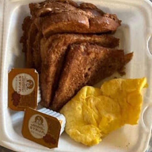 Sammy's Touch French toast and scrambled eggs with two syrup packets in a takeout container.