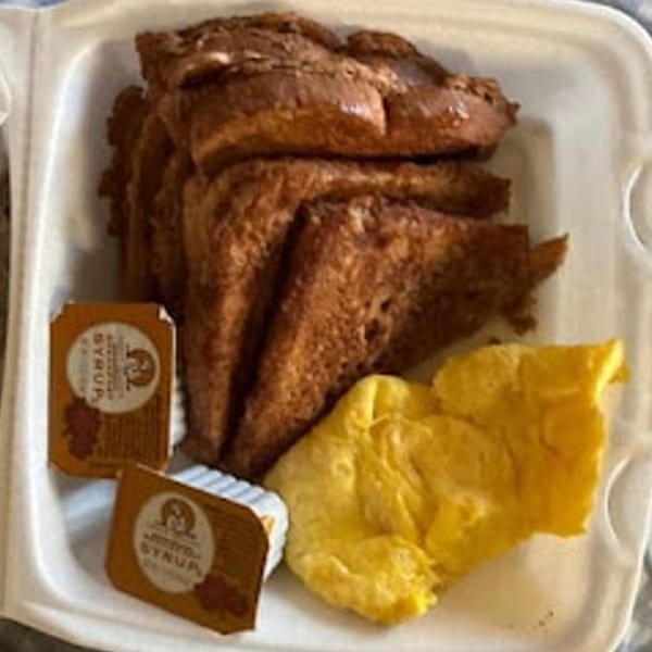 Sammy's Touch French toast and scrambled eggs with two syrup containers in a takeout box.