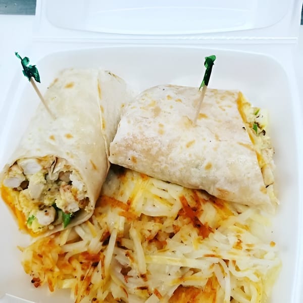 Two breakfast burritos with green picks, served alongside a bed of hash browns in a white container.